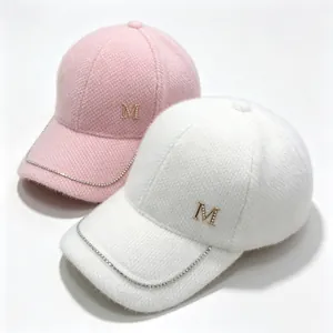 Detail view of fuzzy pink and white winter baseball caps with rhinestone chain trim and M logo