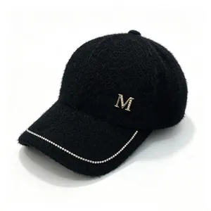 Detail of black mink velvet baseball cap featuring rhinestone M logo and chain decoration.