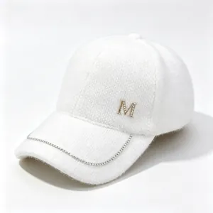 Close-up of white mink velvet baseball cap with rhinestone M logo and chain detail