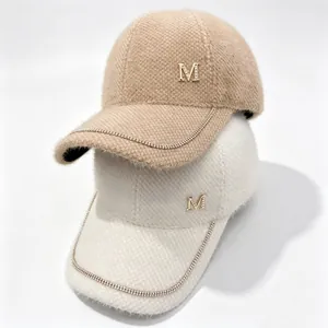 Close-up detail of rhinestone M logo and chain trim on a warm mink velvet baseball cap