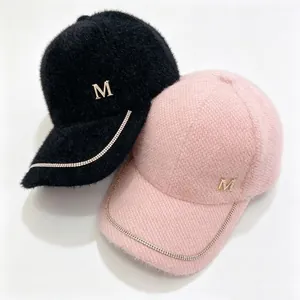 Detailed view of fuzzy mink fur baseball caps featuring rhinestone chain and metal M-logo