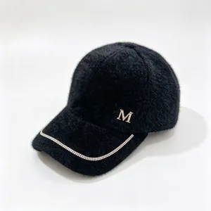 Detailed view of black mink fleece baseball cap with rhinestone M logo and chain trim.
