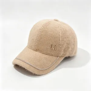 Detail of beige fuzzy mink velvet baseball cap with rhinestone chain and M logo.