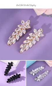 Close-up of elegant wheat-ear hair clips with sparkling clear and black crystals on purple background