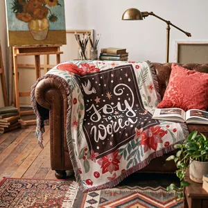 Detail of a woven holiday throw blanket with 'Joy to the World' text on a leather sofa.