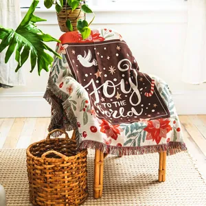 Christmas 'Joy to the World' woven throw blanket draped over a wooden chair in a sunlit room.