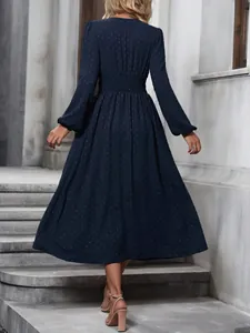 Detailed back view of an elegant navy blue Swiss dot midi dress with lantern sleeves.