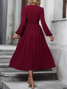 Rear view of a wine red pleated waist dress with lantern sleeves and textured dots.