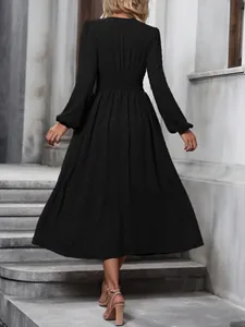 Back view of black lantern sleeve midi dress with smocked waist detail and textured fabric