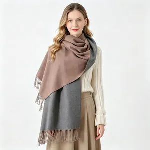 Dettaglio di una donna con sciarpa reversibile in finto cashmere marrone e grigio con nappe.