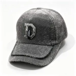 Gros plan détaillé de la casquette en fausse fourrure grise avec logo D et strass brillants