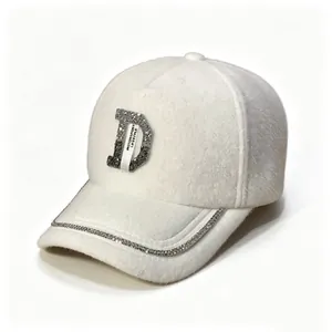 Détail d'une casquette de baseball en imitation vison avec lettre D en strass et bordure brillante.