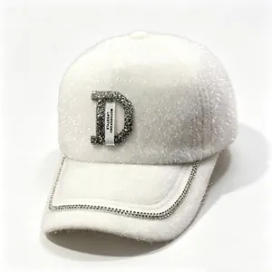 Détail casquette blanche en fausse fourrure de vison avec lettre D en strass et chaîne