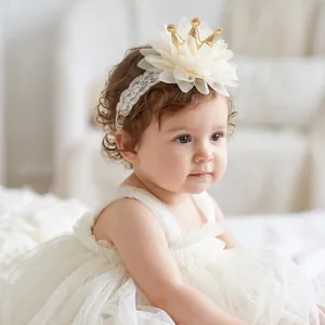 Detailed view of baby girl wearing a floral lace headband with a gold crown decoration