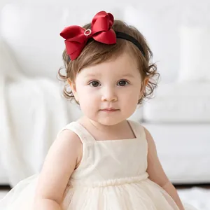Toddler girl wearing a vibrant red satin bow headband with rhinestone detail.
