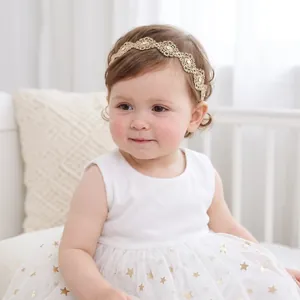 Close-up of a baby wearing a delicate gold lace floral headband with rhinestones