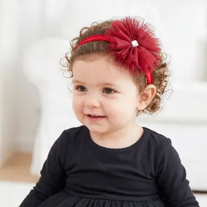 Detailed close-up of a toddler wearing a red mesh floral headband with rhinestone