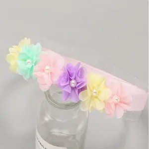 Close-up of sweet pastel chiffon flowers and pearls on a pink baby lace headband