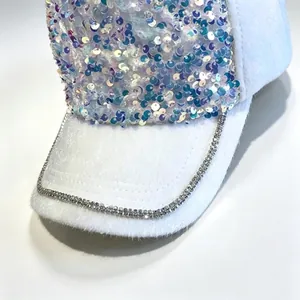 Detailansicht einer weißen Plüsch-Baseballkappe mit bunten Pailletten und glitzerndem Strassbesatz