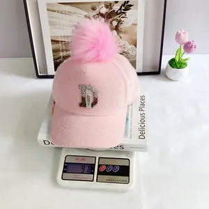 Detail van een roze nertswollen baseballpet met pompon en strass-steentjes D-logo