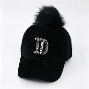 Detailweergave van zwarte winterbontpet met strass-letter D en een grote pluizige pompon