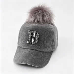 Detailweergave van een grijze nertspluche honkbalpet met strass-letter D en bontpompon