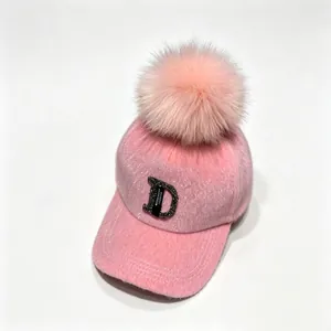 Detail van de roze nertszijde baseballpet met strass letter D en een pluizige pompon