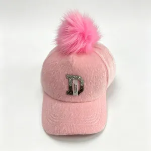 Close-up van roze pluizige honkbalpet met pompon en strass-letter D decoratie