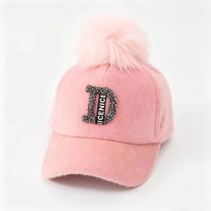 Detailweergave van roze pluizige honkbalpet met strass letter D en pompon van bont