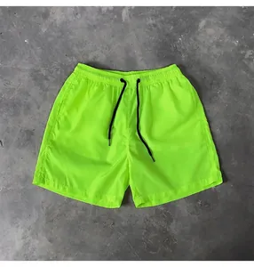 Detail view of neon green quick-dry beach shorts with adjustable black drawstrings