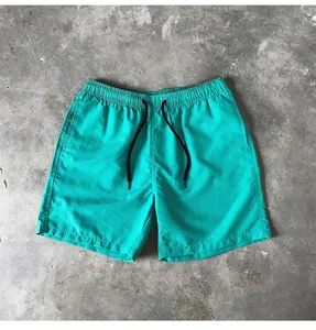 Detailed macro view of teal quick-dry beach shorts with elastic waist and black drawstring