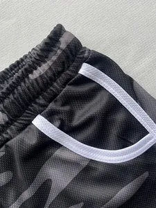 Close-up of camo sports shorts showing waistband and white-trimmed pocket detail.