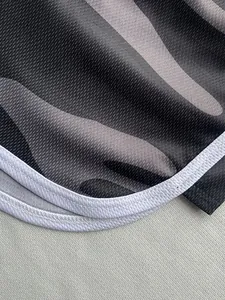 Close-up of breathable mesh fabric on grey camo sports shorts with white piping detail.