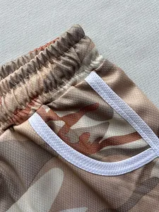 Detail view of camouflage mesh shorts featuring elastic waistband and white pocket trim