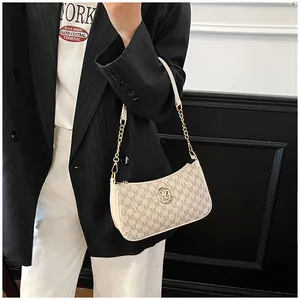 Close-up of a chic beige monogram underarm bag with a gold M logo and chain strap