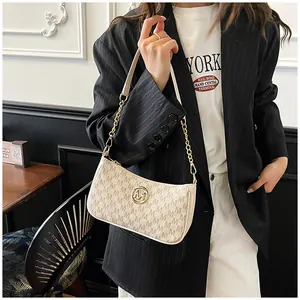 Model carrying a fashionable cream underarm bag with M letter print and gold chain strap