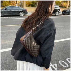 Close-up view of a stylish brown monogram crescent underarm bag with gold chain strap