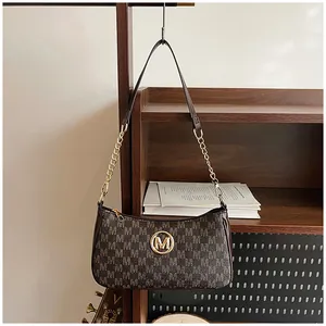 Close-up detail of a brown monogram crescent hobo bag with golden M logo and chain strap