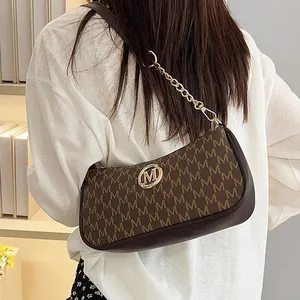 Fashionable crescent underarm bag with M letter print and gold chain strap.