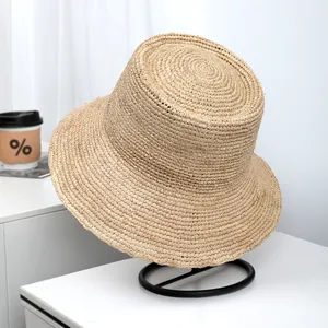 Detailed view of the intricate natural raffia straw weave on a wide-brim sun hat.