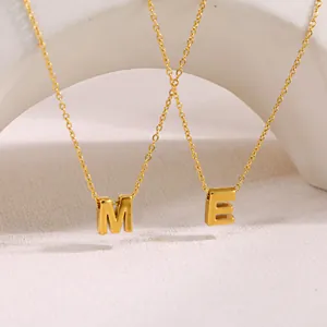 Primer plano de collares de acero inoxidable dorado con colgantes de letras M y E