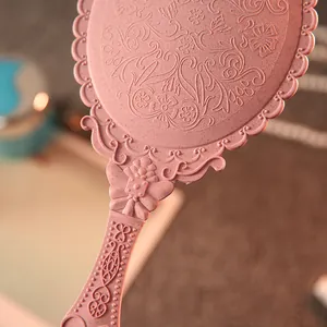 Vintage pink handheld makeup mirror with intricate floral embossed wheat straw texture