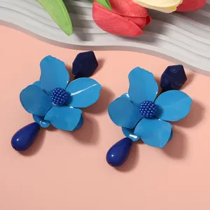 Detailed view of blue flower earrings with faceted studs and teardrop pendants