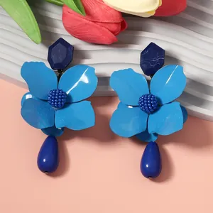 Detailed close-up of blue metal flower earrings featuring geometric and water drop pendants.