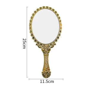 Vintage golden handheld mirror with ornate floral carvings, measuring 25cm in height.