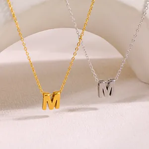 Vista detallada de dos collares minimalistas con la letra M en acabados de oro y plata