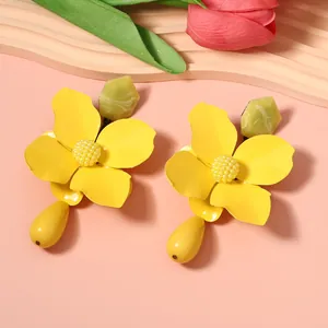 Close-up of yellow metal flower drop earrings with bold statement floral jewelry design.