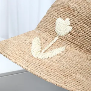 Macro detail showing high-quality raffia weave and white embroidered flower on sun hat