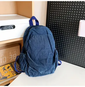 Pequeña mochila vintage de mezclilla lavada colocada en un escritorio con accesorios