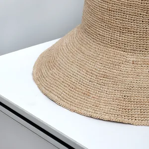 Close-up of the fine raffia weave texture on a wide-brim sun hat for summer vacations.